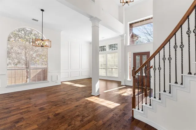 a view of an empty room with wooden floor and a chandelier