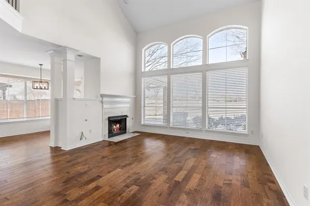 an empty room with wooden floor a fireplace and a window