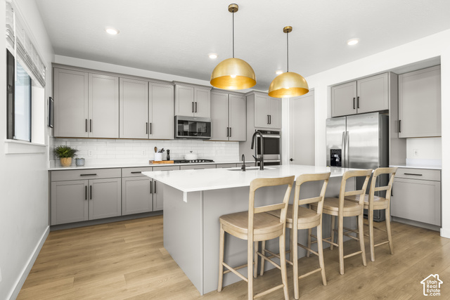 259 South Chamberlain Street Mapleton, UT 84664 - Photo 14 of 54 Kitchen featuring light gray cabinetry, stainless steel appliances, a white subway tile backsplash, a large center island with a white countertop, and wood-finish flooring