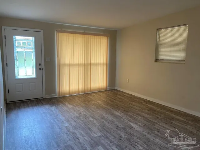 a view of an empty room with wooden floor and a window