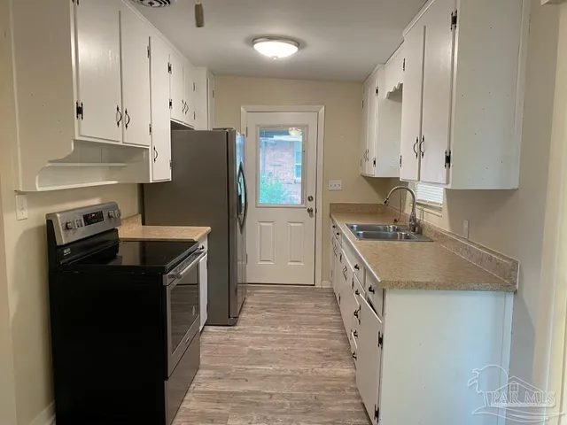 a kitchen with granite countertop a sink stove and refrigerator