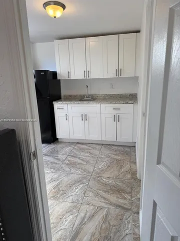 a kitchen with granite countertop a refrigerator sink and cabinets