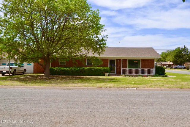 a view of a house with a yard and large trees