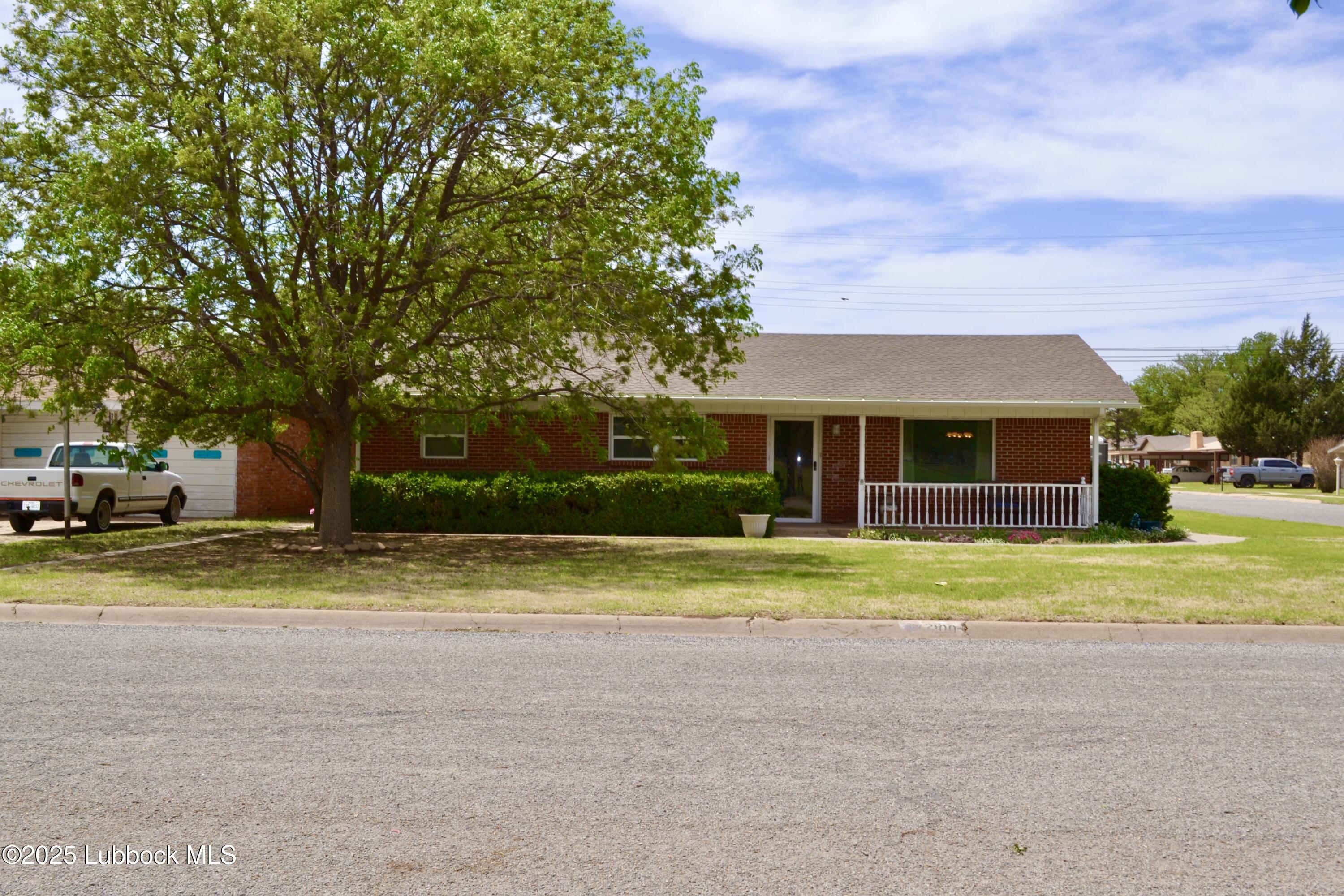 a view of a house with a yard and large trees