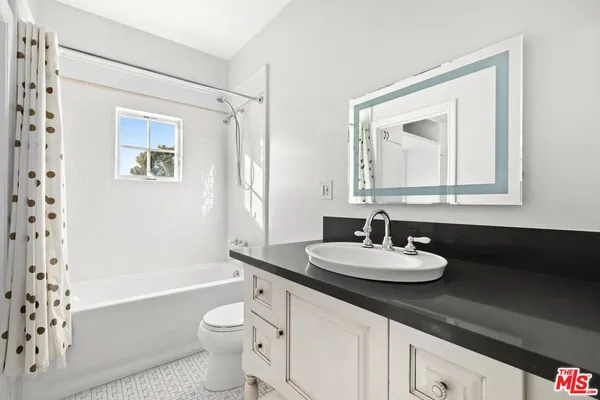 a bathroom with a bathtub a sink a mirror a toilet and a window