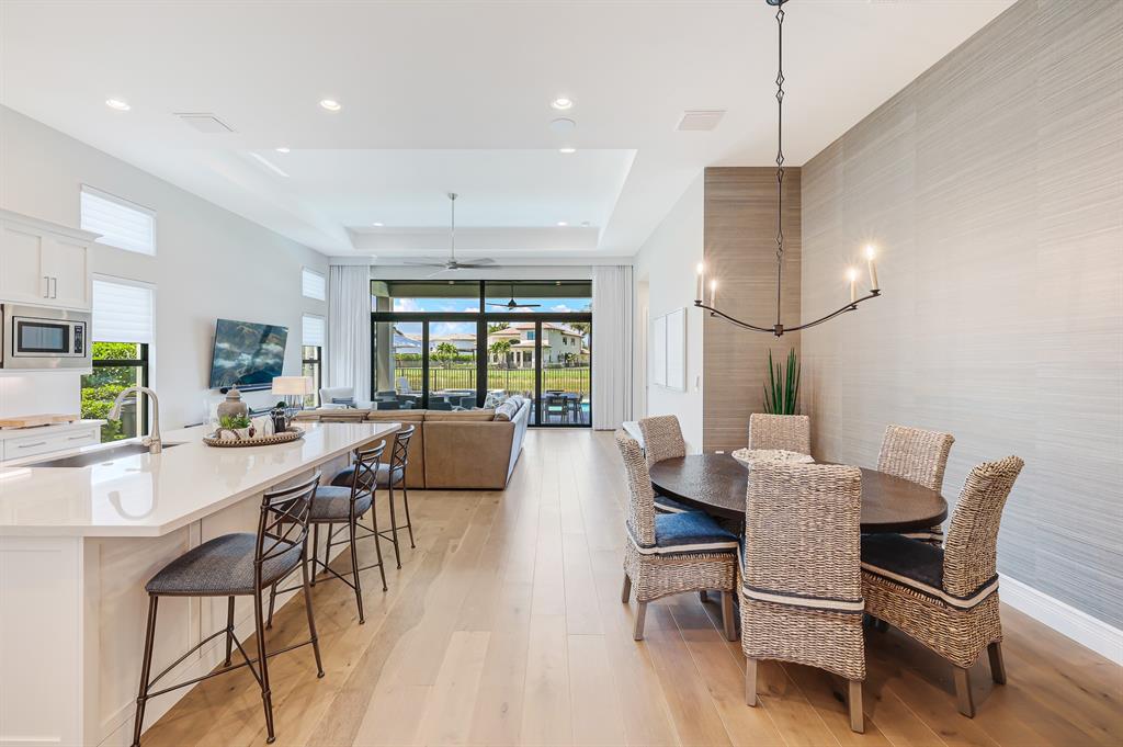 17401 Santaluce Manor Boca Raton, FL 33496 - Photo 8 of 84 a view of a dining room and livingroom with furniture wooden floor a rug a flat screen tv a painting and a chandelier
