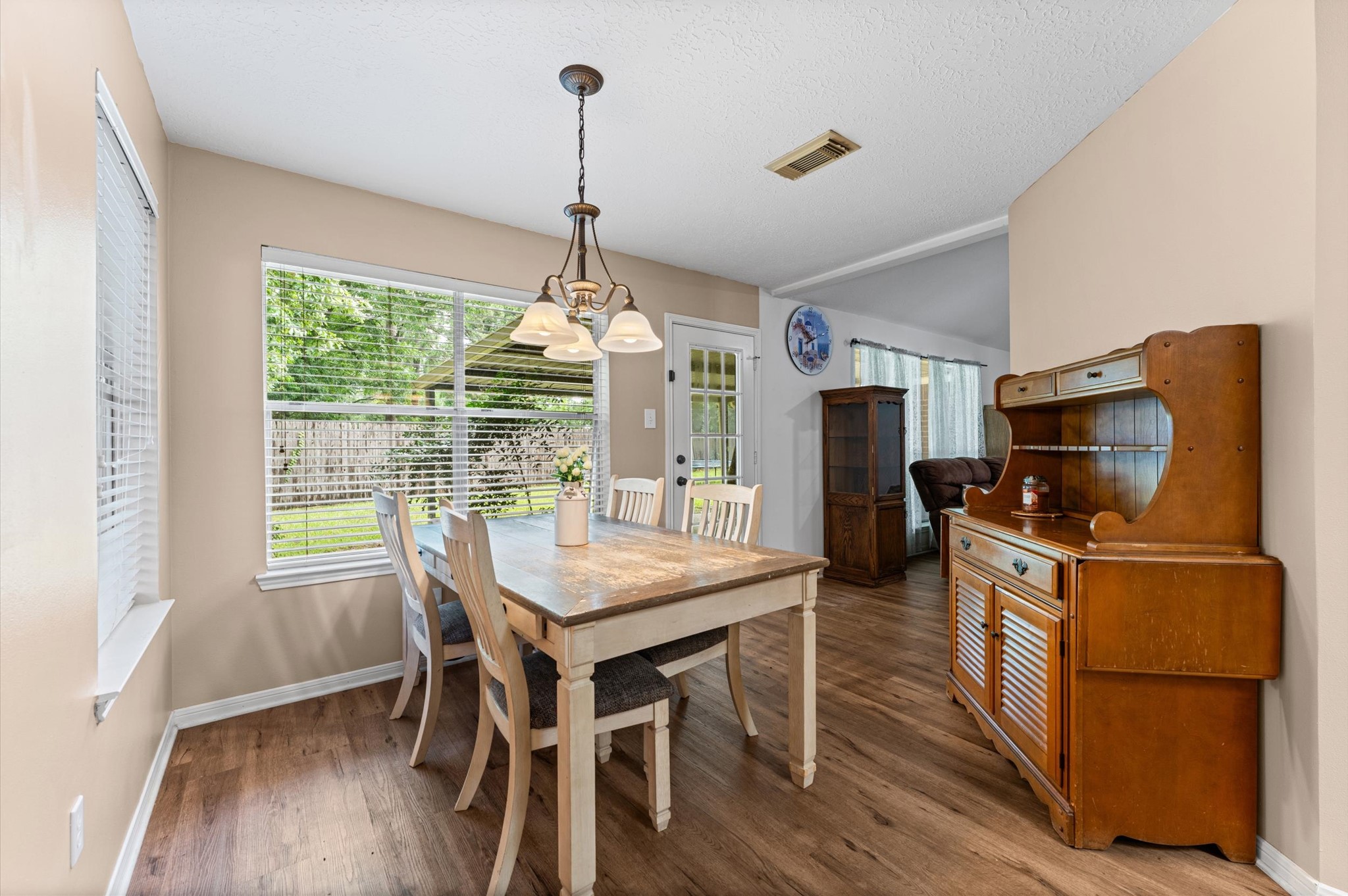 17618 Mill Springs Drive Spring, TX 77379 - Photo 7 of 26 This dining area features a wooden table with chairs, laminate flooring, and ample natural light from large windows overlooking a lush backyard. A vintage hutch adds charm, and the area opens into a cozy living space.