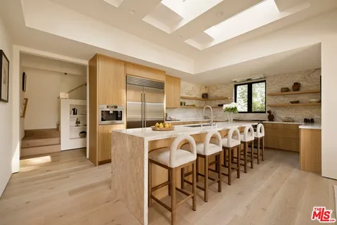 a kitchen with stainless steel appliances kitchen island granite countertop a table chairs and a refrigerator