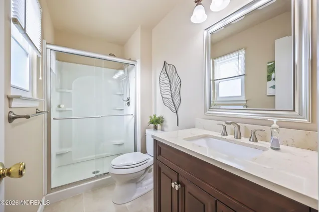 a bathroom with a granite countertop sink a toilet and shower