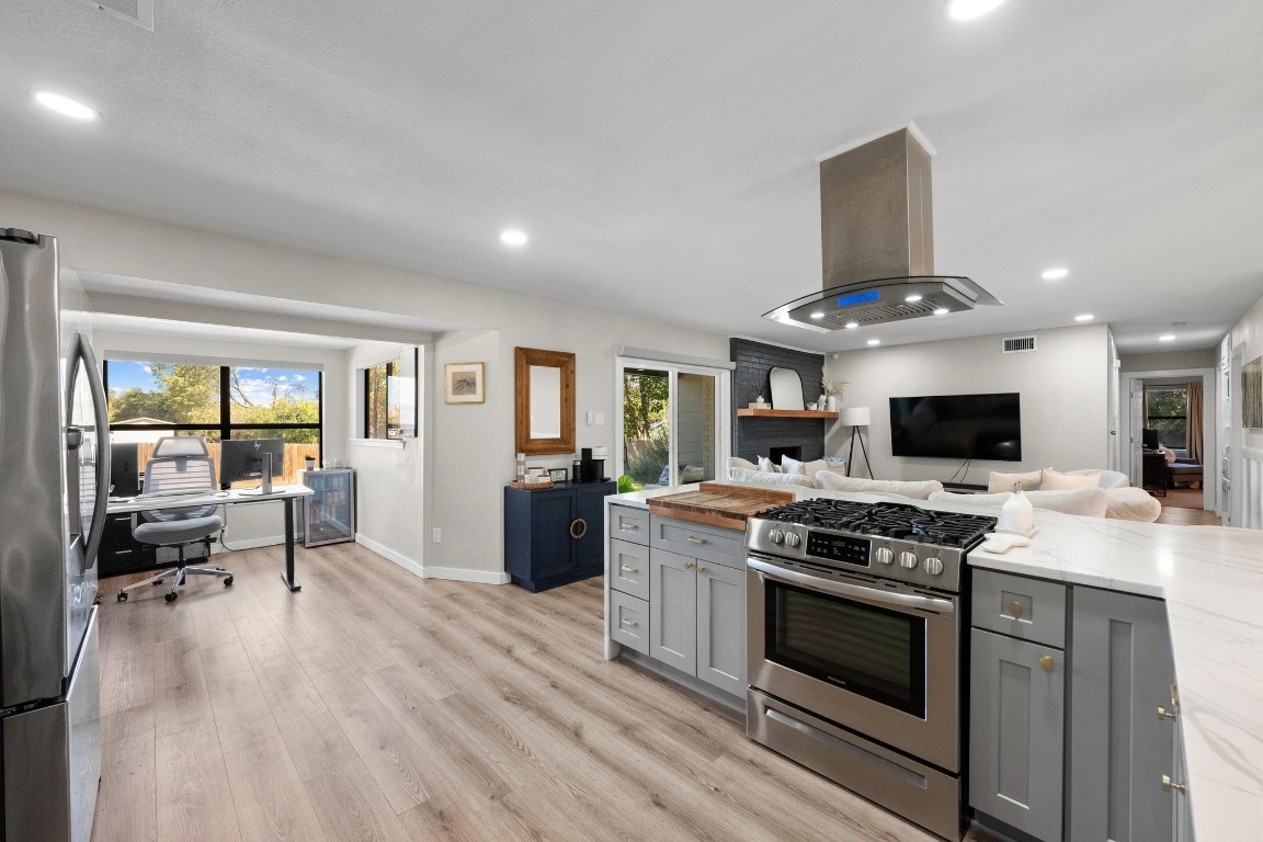 1006 Hollybluff Street Austin, TX 78753 - Photo 10 of 27 Kitchen featuring appliances with stainless steel finishes, gray cabinets, island range hood, light wood-style floors, and recessed lighting