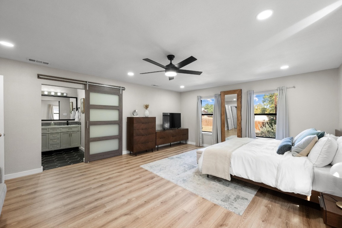 1006 Hollybluff Street Austin, TX 78753 - Photo 15 of 27 Bedroom featuring a barn door, light wood-style floors, recessed lighting, a ceiling fan, and ensuite bath