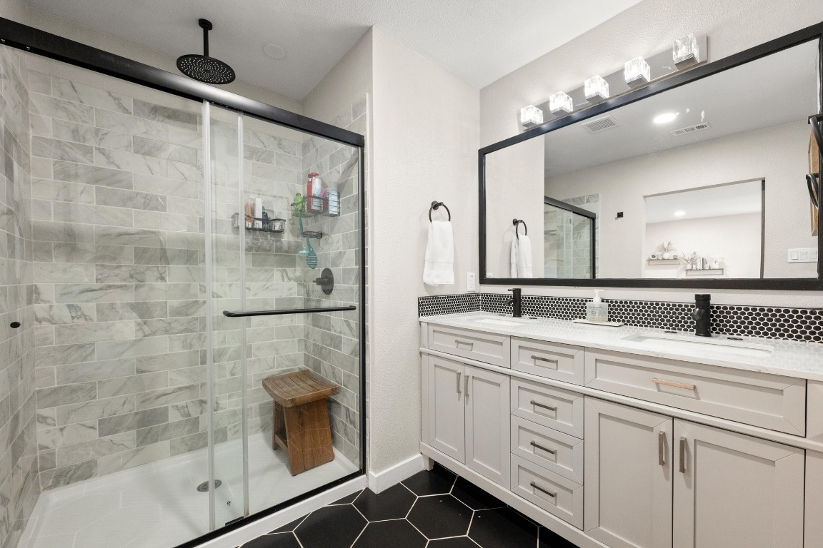 1006 Hollybluff Street Austin, TX 78753 - Photo 17 of 27 Full bath with double vanity, dark tile patterned floors, and a stall shower