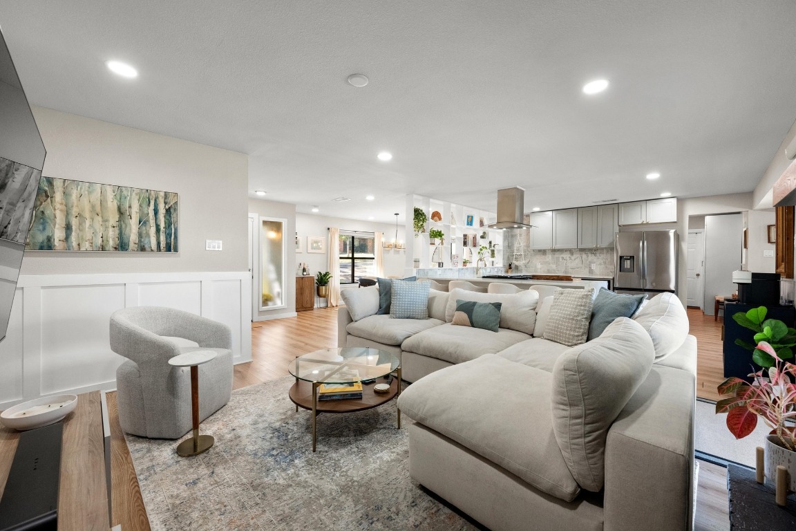 1006 Hollybluff Street Austin, TX 78753 - Photo 5 of 27 Living area featuring wood finished floors, a wainscoted wall, recessed lighting, a decorative wall, and a chandelier
