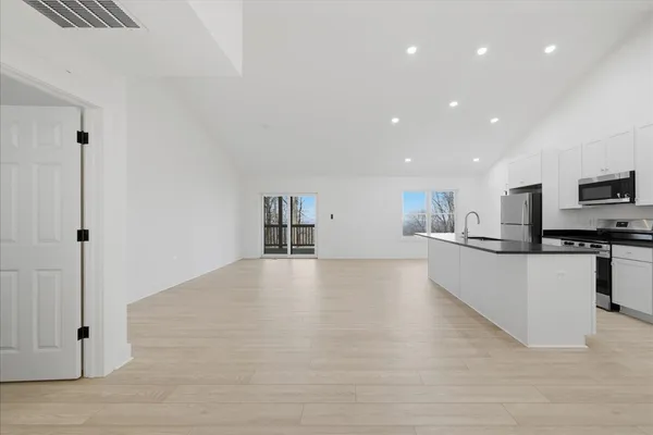 a large kitchen with stainless steel appliances a large counter top a stove and a wooden floors