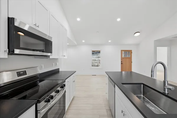 a kitchen with stainless steel appliances a stove top oven a sink and a refrigerator