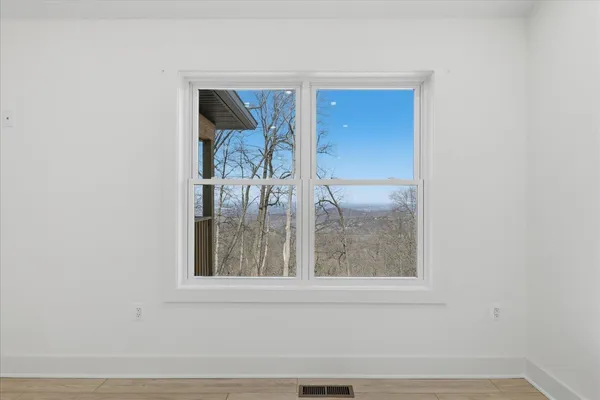 a view of an empty room with a window and wooden floor