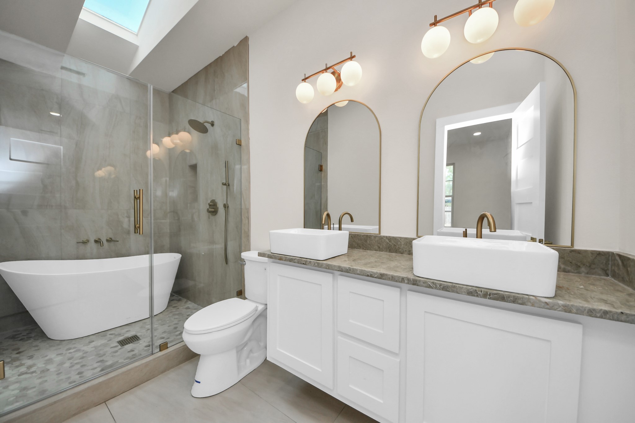 427 North Milby Street Houston, TX 77003 - Photo 15 of 44 Spa-inspired bathroom featuring dual vanities, designer lighting, and elegant finishes throughout. Luxurious walk-in glass shower and freestanding soaking tub create the perfect retreat. Bright, modern, and thoughtfully designed for everyday comfort.