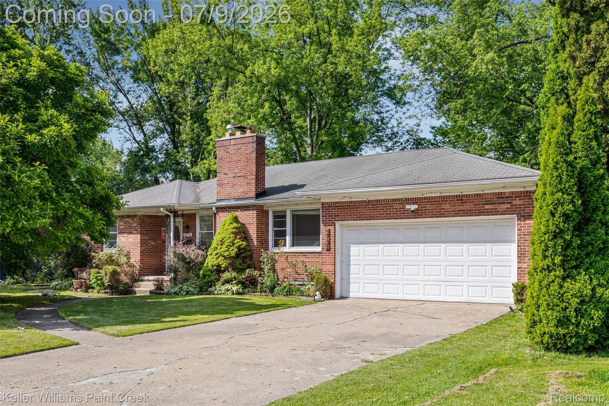 2731 Crooks Road Royal Oak, MI 48073 - Photo 28 of 34 Brick exterior residence featuring an attached garage with a white panel door, a grey shingle roof, a prominent brick chimney, and mature landscaping