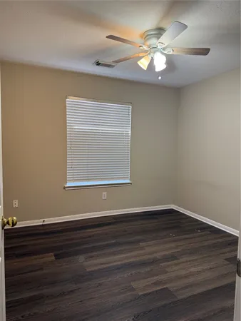 a view of an empty room with wooden floor and a chandelier fan