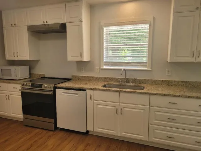 a kitchen with granite countertop white cabinets and a stove