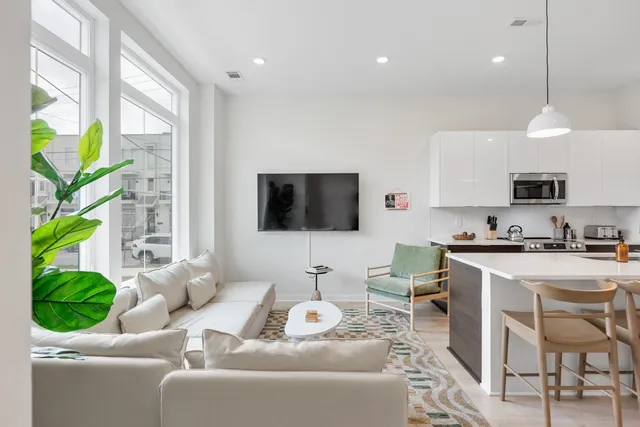 a living room with furniture a flat screen tv and a floor to ceiling window