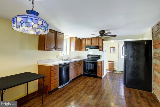 a kitchen with stainless steel appliances granite countertop a refrigerator a sink dishwasher a stove and a dining table with wooden floor