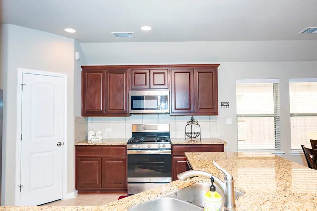 a kitchen with stainless steel appliances granite countertop a stove top oven a sink and dishwasher