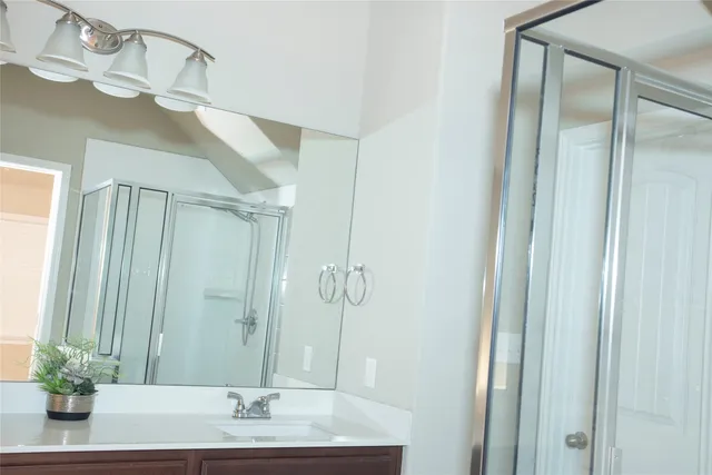 a bathroom with a granite countertop sink a mirror and a shower
