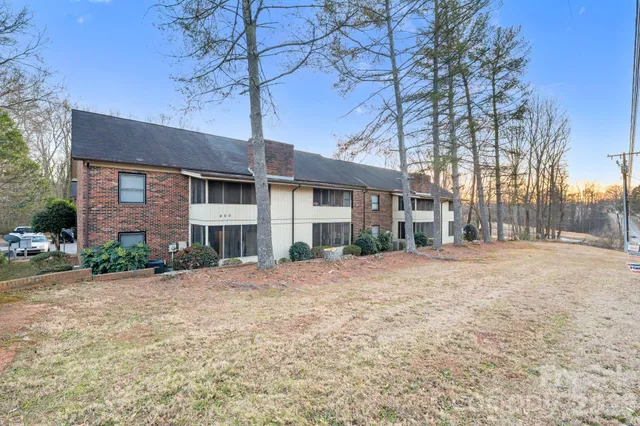 a front view of a house with a dirt yard and a large tree