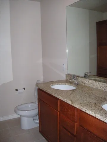 a bathroom with a granite countertop toilet a sink and a mirror