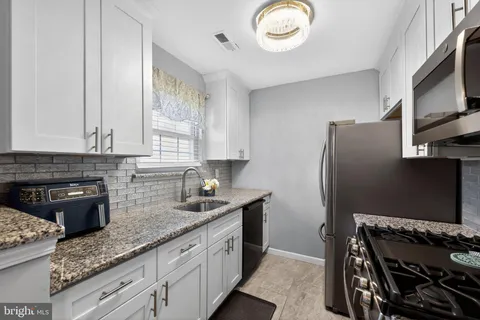 a kitchen with granite countertop a refrigerator stove and sink