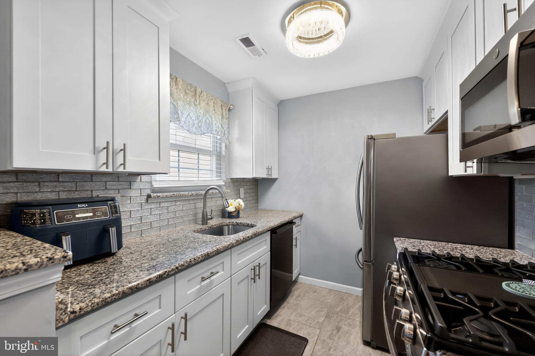 213 Tavistock Road Cherry Hill, NJ 08034 - Photo 7 of 24 a kitchen with granite countertop a refrigerator stove and sink