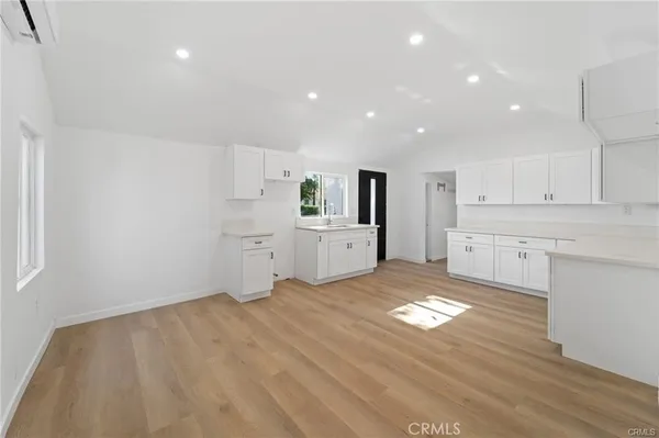 a view of a kitchen with a sink and dishwasher stove top oven with wooden floor