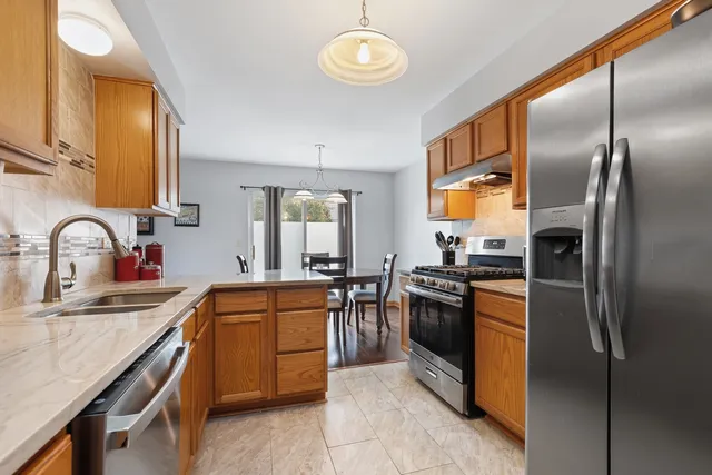 a kitchen with stainless steel appliances granite countertop a sink a stove and refrigerator