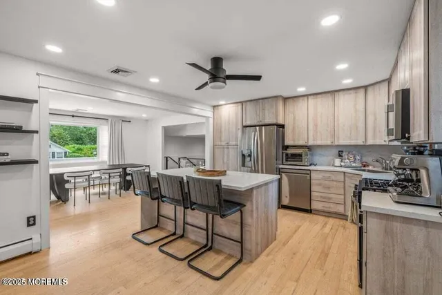 a kitchen with stainless steel appliances kitchen island granite countertop a stove a sink a dining table and chairs with wooden floor