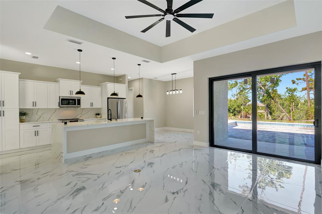 212 Fairway Road Rotonda West, FL 33947 - Photo 21 of 65 a large white kitchen with kitchen island a large window a sink and stainless steel appliances