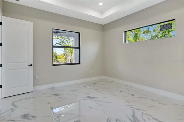an empty room with a chandelier fan and windows