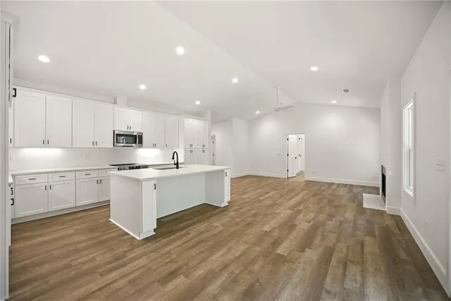 a large white kitchen with kitchen island a sink stainless steel appliances and cabinets