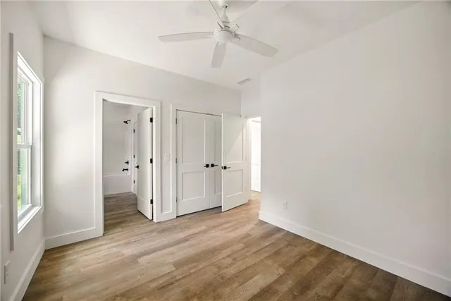 an empty room with wooden floor and ceiling fan