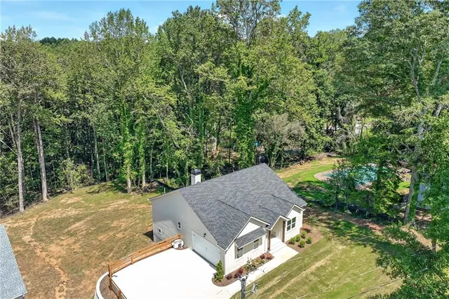 aerial view of a house with yard and trees in the background