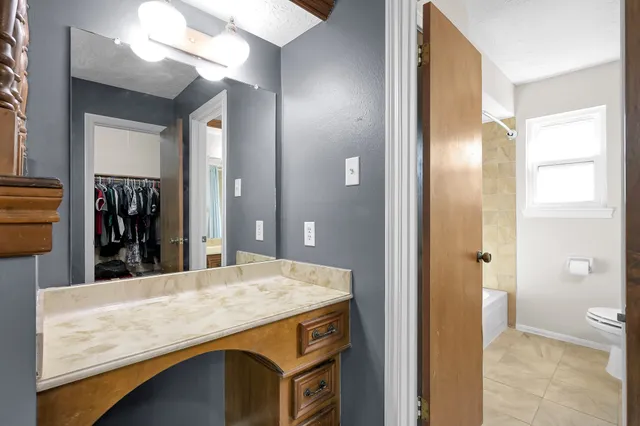 a bathroom with a granite countertop sink a toilet and shower