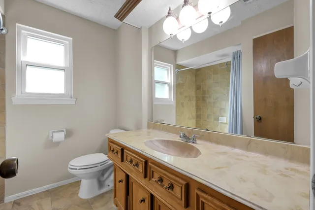 a bathroom with a granite countertop sink a toilet and a mirror