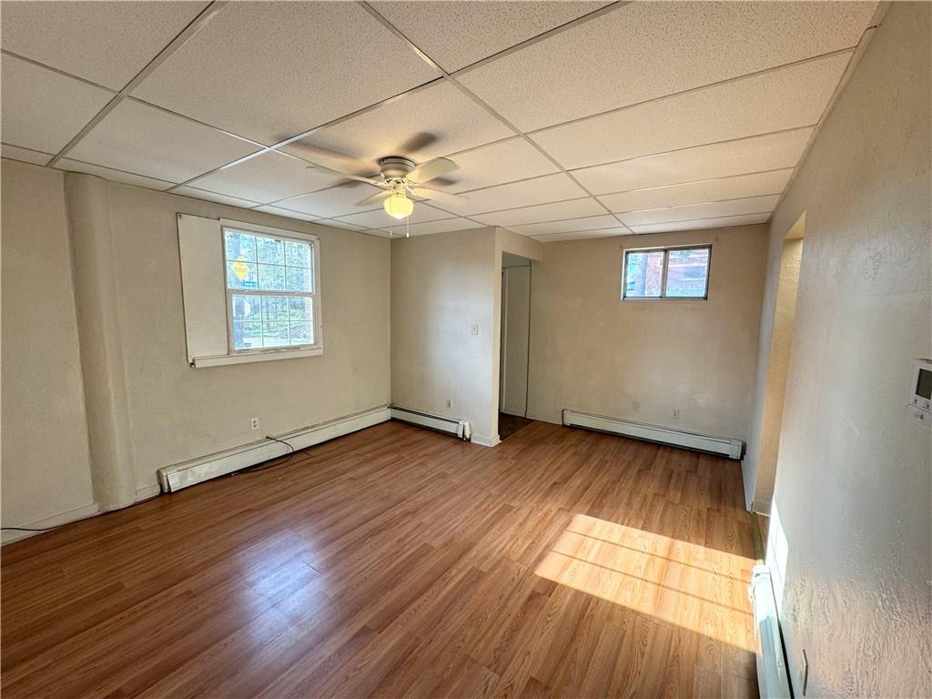 340 Rochelle Street, Unit 1 Pittsburgh, PA 15210 - Photo 3 of 5 an empty room with wooden floor chandelier fan and windows