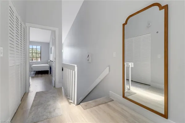 a view of a hallway with wooden floor and a living room