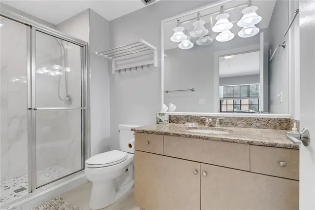 a bathroom with a granite countertop sink mirror vanity and toilet