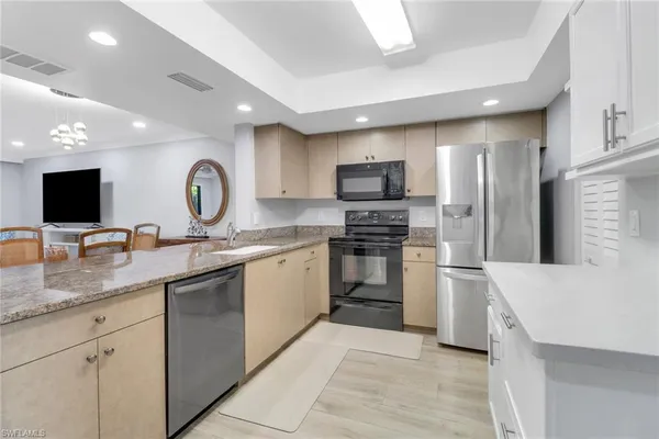 a kitchen with granite countertop a sink stainless steel appliances and white cabinets