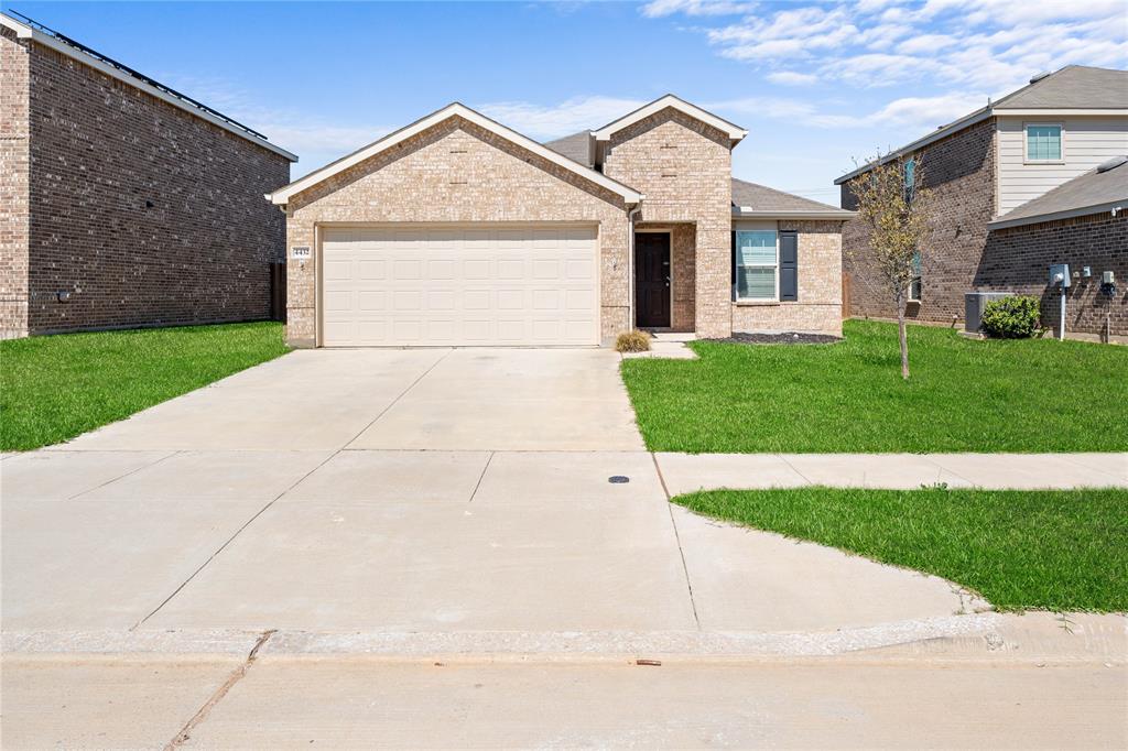 View of front of home featuring a front yard, driveway, an attached garage, and brick siding