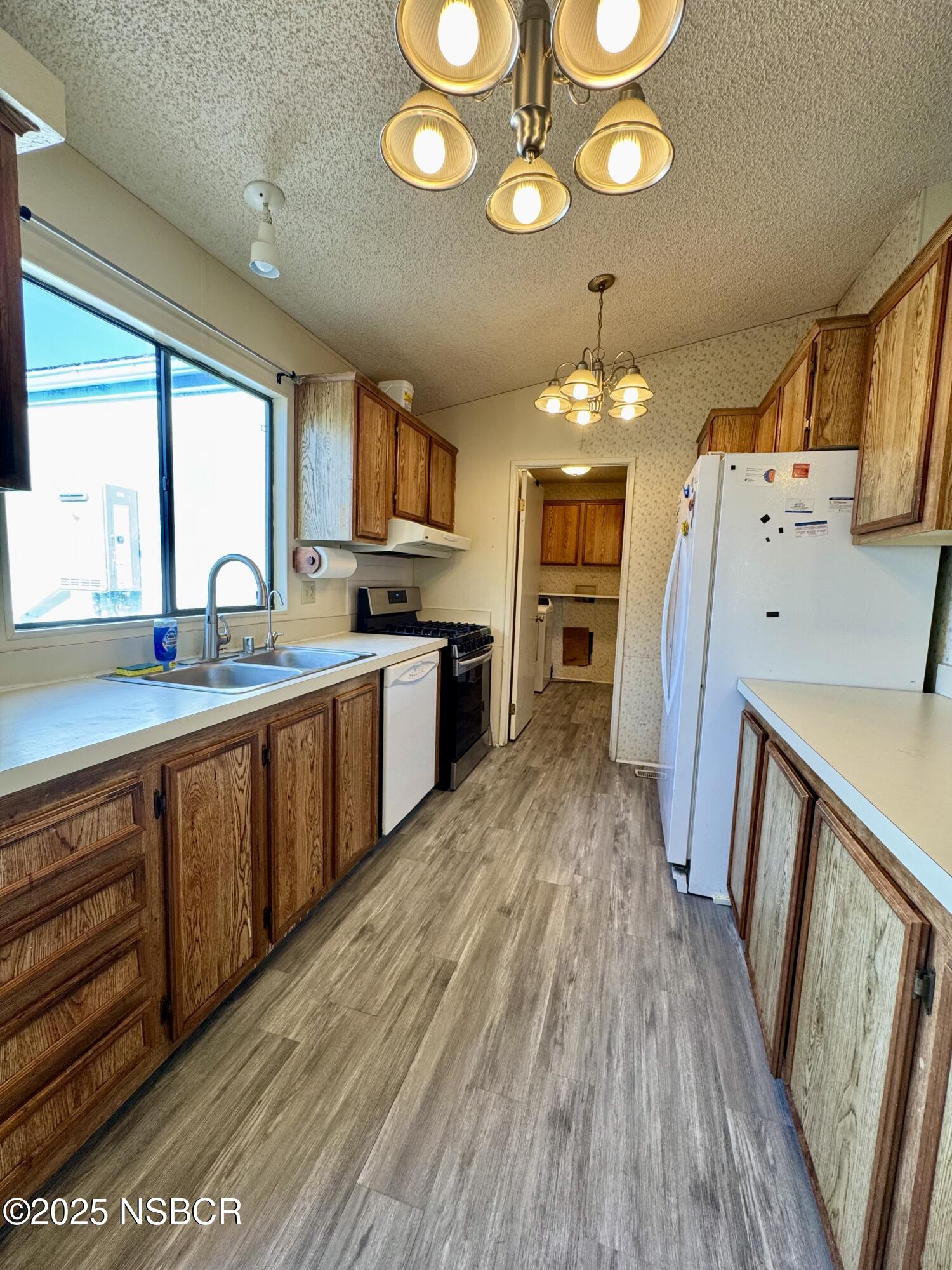 1317 V Street, Unit 58 Lompoc, CA 93436 - Photo 9 of 34 a large kitchen with a lot of counter space and a wooden floor