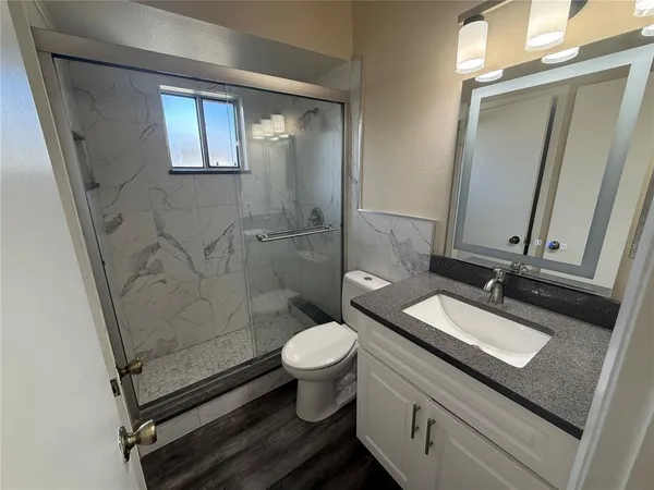 a bathroom with a granite countertop sink toilet and shower