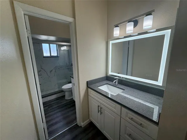 a bathroom with a granite countertop sink toilet and shower